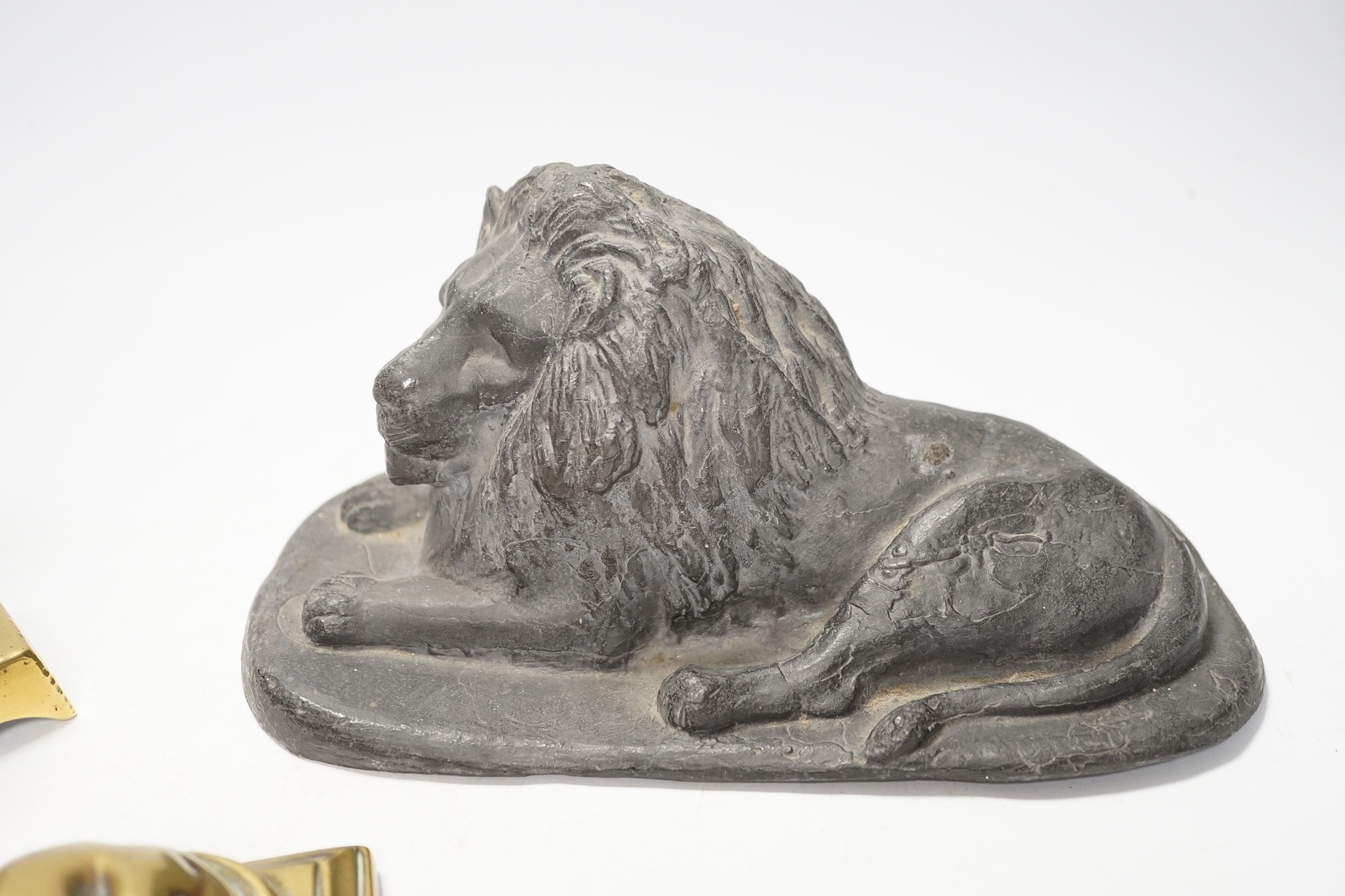 A 19th century brass recumbent lion, a similar cast iron lion and a smaller lion, largest 22cm wide